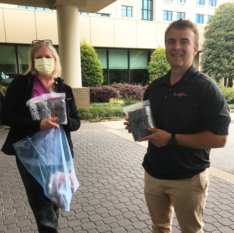 A Focus Inc employee delivers bags of 3D-printed face mask extenders to a local hospital representative